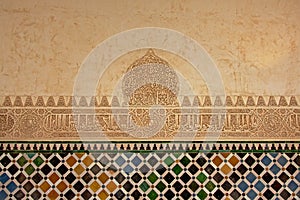 Moorish decorations with stone carvings and tiles on a wall in Nasrid palace, Alhambra, Granada
