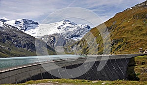 Mooserboden dam on the lake and the snowy peaks of the Hohe Tauern in the background.