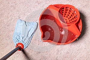 mop cleaning linoleum flooring near red bucket