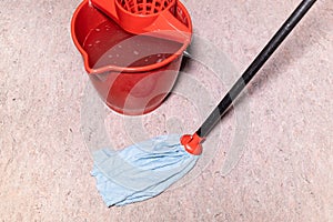 mop cleans linoleum flooring near red bucket