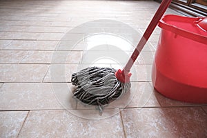 Mop and red bucket of cleaning on the tiled floor ready to clean close-up.  Cleaning services. Home interior