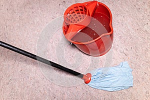 mop washes linoleum floor near red bucket