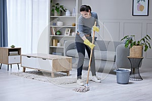 Mopping, floor and woman cleaning the living room of her house. Cleaner or professional worker with apartment service