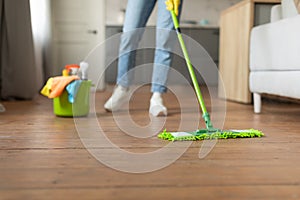 Mopping hardwood floor with cleaning supplies nearby