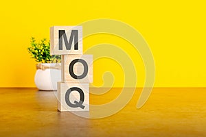 moq - text on wood cubes stack, yellow background