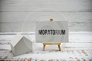 Moratorium text with calculator and house model on wooden background