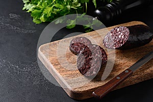 Morcilla blood sausage on wooden tray on black background. Close up.