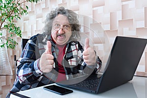 Morden pensioner with his fingers up and a tongue working at the laptop