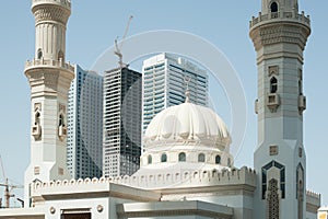 Mordern arabic mosque and high-rise buildings on the background