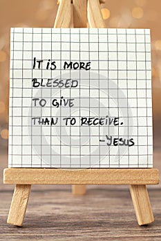 It is more blessed to give, than to receive, Jesus Christ, handwritten biblical quote on paper note with bokeh background