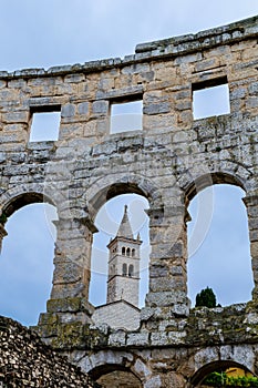 More modern church steeple seen through the ancient Pula Arena arch