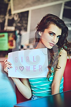 More power to me. Cropped portrait of an attractive young woman holding up a sign in a retro diner.