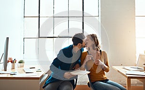 More than an office romance. young couple kissing while working together in their modern office.
