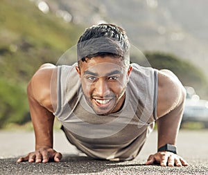 The more you do it, the more bearable it becomes. an athletic young man doing push-ups outside.