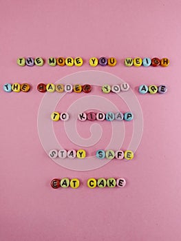 The more you weigh the harder you are to kidnap stay safe eat cake  funny sign with colorful letters on a pink background