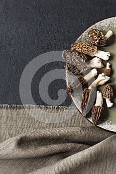 Morel mushrooms on a plate on black background