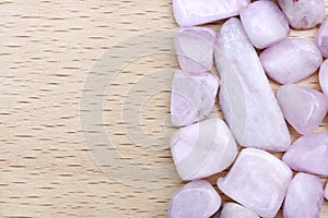 Morganite heap stones texture on half light varnished wood background. Place for text. Horizontal orientation