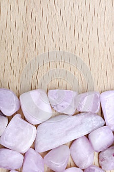 Morganite heap stones texture on half light varnished wood background. Place for text. Vertical orientation