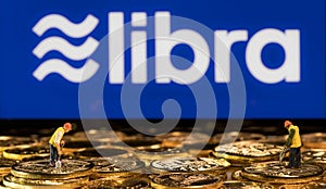 Golden coins stacked in front of tablet computer for Libra cybercurrency