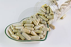 Moringa capsules on small heart pattern bowl
