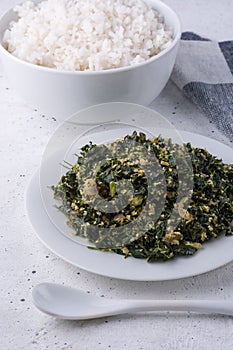 Moringa or drumstick leaves dish, tempered vegetarian dish on a white surface