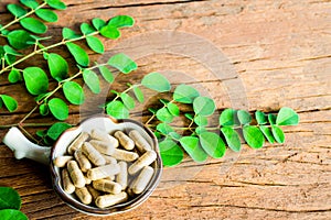 Moringa leaves with Moringa capsules on old wood. Healthy herbs