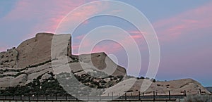 Mormon Rocks in front of railroad tracks under pink sunset clouds in California high desert just outside of San Bernardino