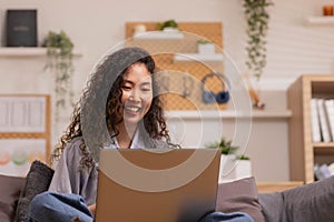 In the morning,Asian working woman relaxes on the sofa with her laptop, working from home