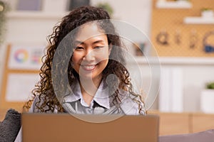 In the morning,Asian working woman relaxes on the sofa with her laptop, working from home