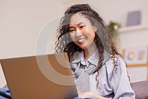 In the morning,Asian working woman relaxes on the sofa with her laptop, working from home