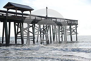 Waves crash the beach pier pilings and then onto the sandy shoreline off the Atlantic Seaboard. photo