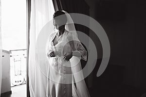 Morning of beautiful bride. Woman in white negligee in hotel