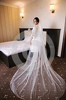 Morning of beautiful bride. Woman in white negligee in hotel. Back view