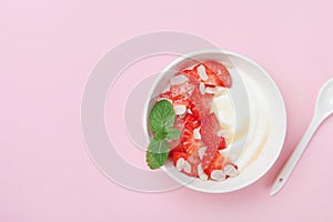 Morning breakfast bowl with greek yogurt, strawberry and honey on a pink table. Top view.