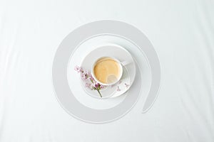 Morning breakfast with coffee cup and lilac branches on white background. Flat lay, top view women background. Minimal concept,