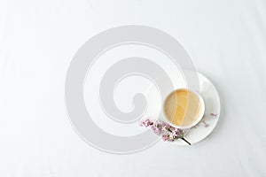 Morning breakfast with coffee cup and lilac branches on white background. Flat lay, top view women background. Minimal concept,