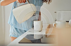Morning, breakfast coffee and female hands pouring water in cup from retro kettle in kitchen at home. Woman in pajamas