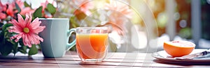 Morning breakfast, glass with orange juice, cup of coffee and orange fruit on plate on wooden table in garden or backyard. Summer