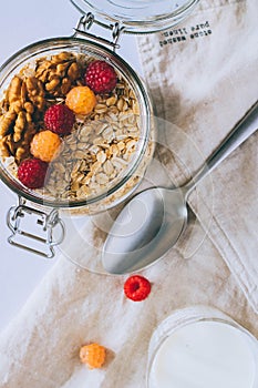 Morning breakfast, oatmeal with red and yellow raspberries and walnuts in a glass ja