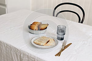 Morning breakfast with pears fruit composition. Bread toast, folded newspapers and glass of water on white linen table