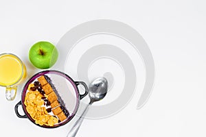 Morning breakfast. Spoon, bowl with homemade yogurt and cornflakes, raisins, almonds, green apple and orange juice on white