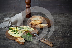 Morning breakfast of a traditional French omelet with toasts and butter, chopped parsley and a white porcelain cup of coffee on a