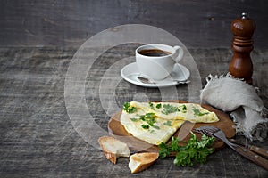 Morning breakfast of a traditional French omelet with toasts and butter, chopped parsley and a white porcelain cup of coffee on a
