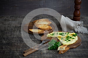 Morning breakfast of a traditional French omelet with toasts and butter, chopped parsley and a white porcelain cup of coffee on a