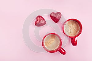 Morning breakfast for Valentines day. Two cups of coffee and red hearts on pink background top view. Flat lay