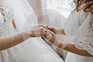 Morning of the bride. The bridesmaid helps the bride, supports her and holds her hands.