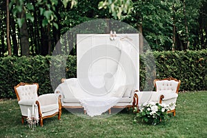 Morning of bride, gathering bride in nature, photo zone. Furniture, screen, flowers, wedding dress and shoes. Eco style wedding.