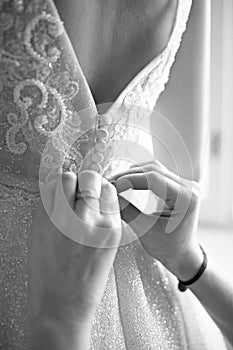 Morning of the bride, mother buttoning a corset on her daughter`s whip on the eve of the wedding ceremony, back view, focus on but