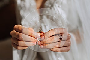 Morning of the bride before the wedding. A beautiful young woman with a long veil in a white robe on a dark background