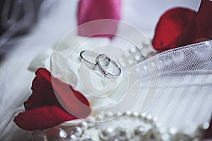 Morning bride. Wedding rings, rose petals and pearl necklace. We